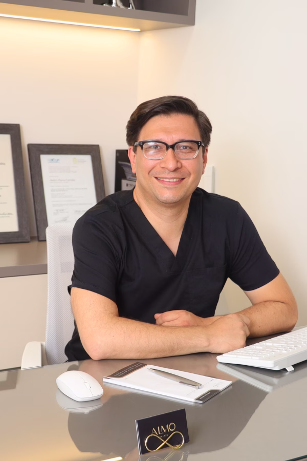 Dr. Andrés Parra en consulta personalizada con paciente en su consultorio moderno en Bogotá